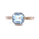 An unmarked gold blue topaz dress ring, set with a square step cut topaz, setting height 7.7mm, size