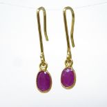 A pair of unmarked gold ruby pendant earrings, set with oval cut rubies, shepherd hook fittings,