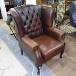 A button-back brown leather upholstered wing armchair, on cabriole legs, by Thomas Lloyd