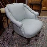 An Edwardian upholstered low armchair on turned legs