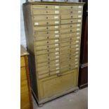 A Victorian pine bank of 32 drawers, with cupboard under, on bun feet, W84cm, H162cm, D42cm