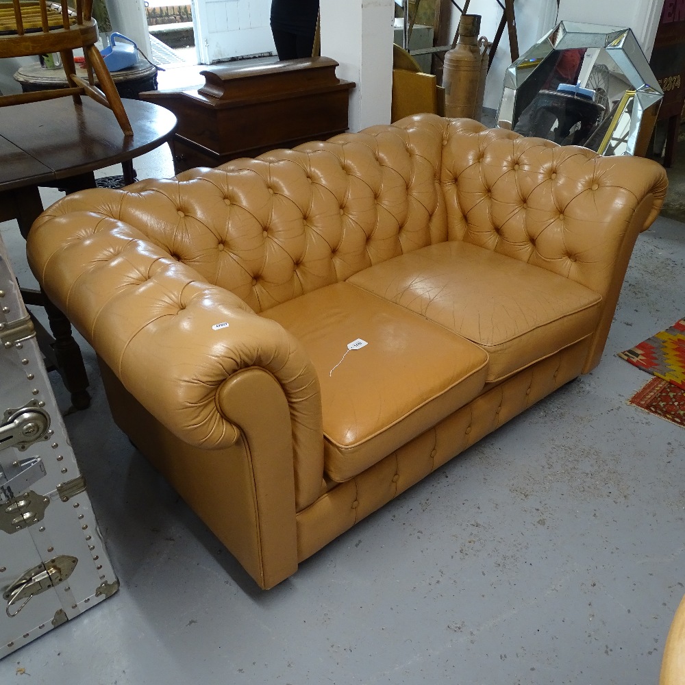 A salmon coloured button-backed leather upholstered 2-seater rollover arm settee, L150cm, H67cm,
