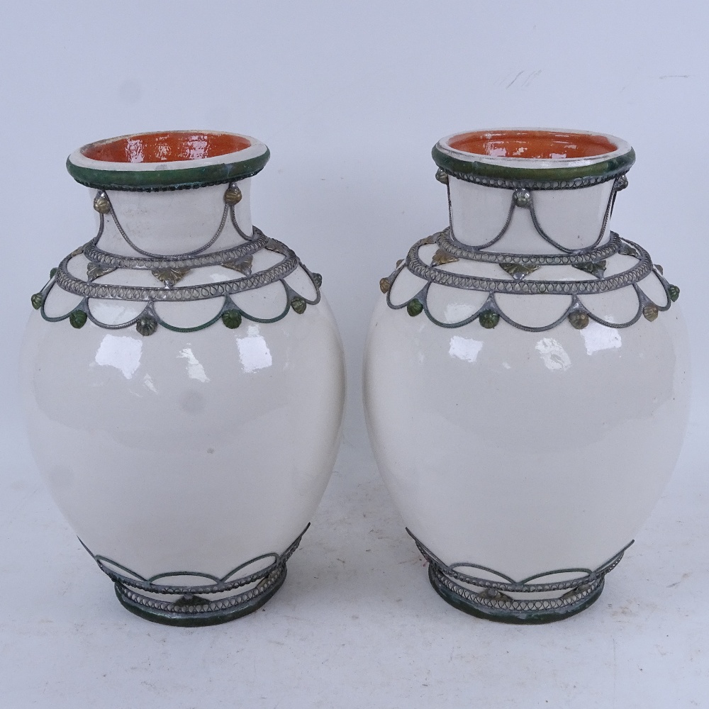 A pair of Middle Eastern glazed terracotta vases with metal mounts, height 28cm