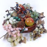 A wooden bowl containing bunches of hardstone grapes and other fruit