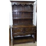 A 1920s oak 2-section dresser, with a boarded open plate rack, 2 moulded panelled cupboard doors