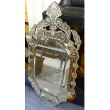 A Venetian style wall mirror of shaped form, with bevelled glass panel, L95cm