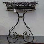 An oval wirework planter on scrolled wrought-iron stand, W70cm, H90cm