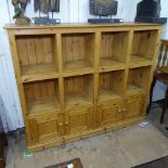 A large polished pine sectional bookcase, with cupboards to the bottom, W173cm, H142cm, D41cm