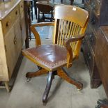 An early 20th century oak and studded leather-seated swivel desk chair, on a splayed leg base