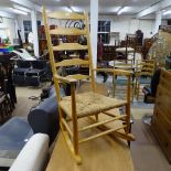 An Arts and Crafts Cotswold School style ladder-back rocking chair in ash, with rush seat,