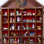 A wall-hanging glazed display cabinet, containing various collectables, including elephant