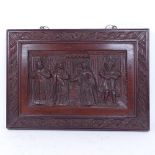 A Victorian relief carved mahogany wall plaque, depicting a Tudor interior scene, in carved