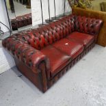 A red leather upholstered 3-seater Chesterfield settee, with rollover arms, L190cm, H70cm, seat