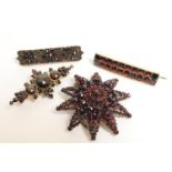 Four Victorian garnet brooches, one being a star form backed in silver, with safety chain, 44mm