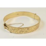 Modern 9ct gold hinged bangle, with scroll decoration, safety chain, 6cm, weight approx. 20.6g (