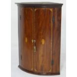 George III mahogany and inlaid bowfront hanging corner cupboard, circa 1785, having a cavetto