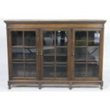 George V glazed bookcase, having a dentil frieze over three glazed doors opening to adjustable