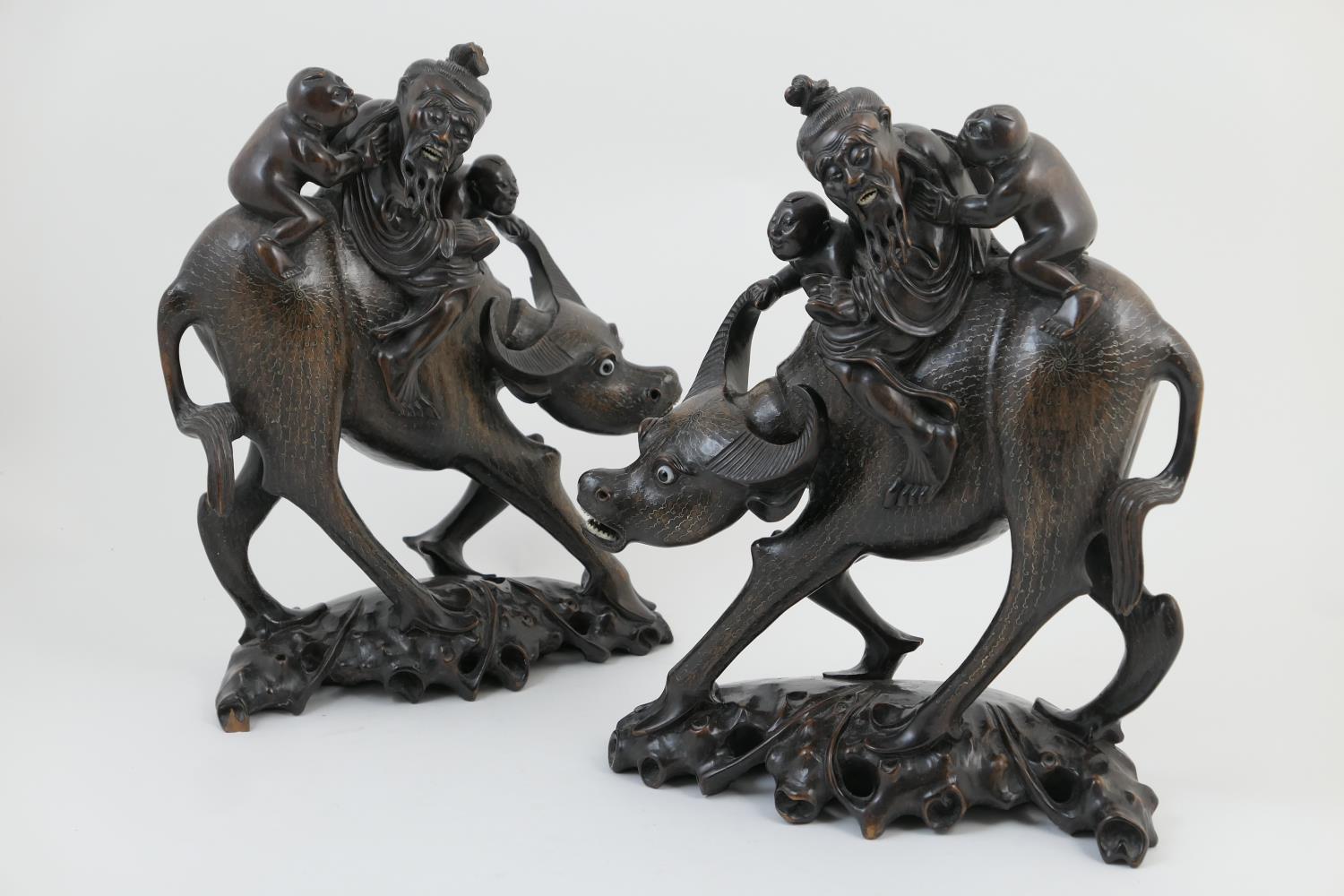 Pair of Chinese carved wooden water buffalo, circa 1900, ridden along by an elderly traveller with