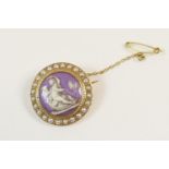 Edwardian enamelled pearl circular brooch, centred with a roundel depicting a cherub being drawn