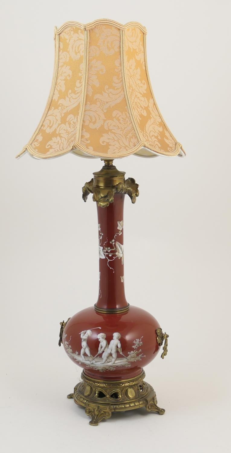 Unusual French brass mounted porcelain table lamp, decorated with cherubs idling at hockey,