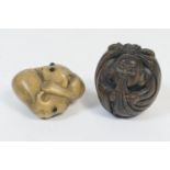 Two Japanese carved wooden netsukes, one carved as two embracing rabbits, the other a deity