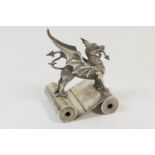 Welsh interest: Silver dragon form paperweight, the dragon standing astride two paper scrolls, by