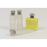 Four silver topped glass scent bottles, including a yellow moulded glass example decorated with