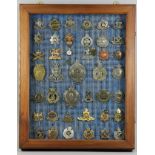 Two framed collections of British Military cap and other badges, and a belt with applied badges,