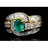An Emerald and Diamond Ring, Modern, in 18ct gold mount, set with a central oval emerald,