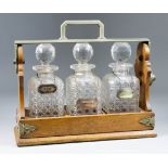 A Late Victorian Oak and Plated Metal Three Bottle Tantalus, retailed by The Goldsmiths &