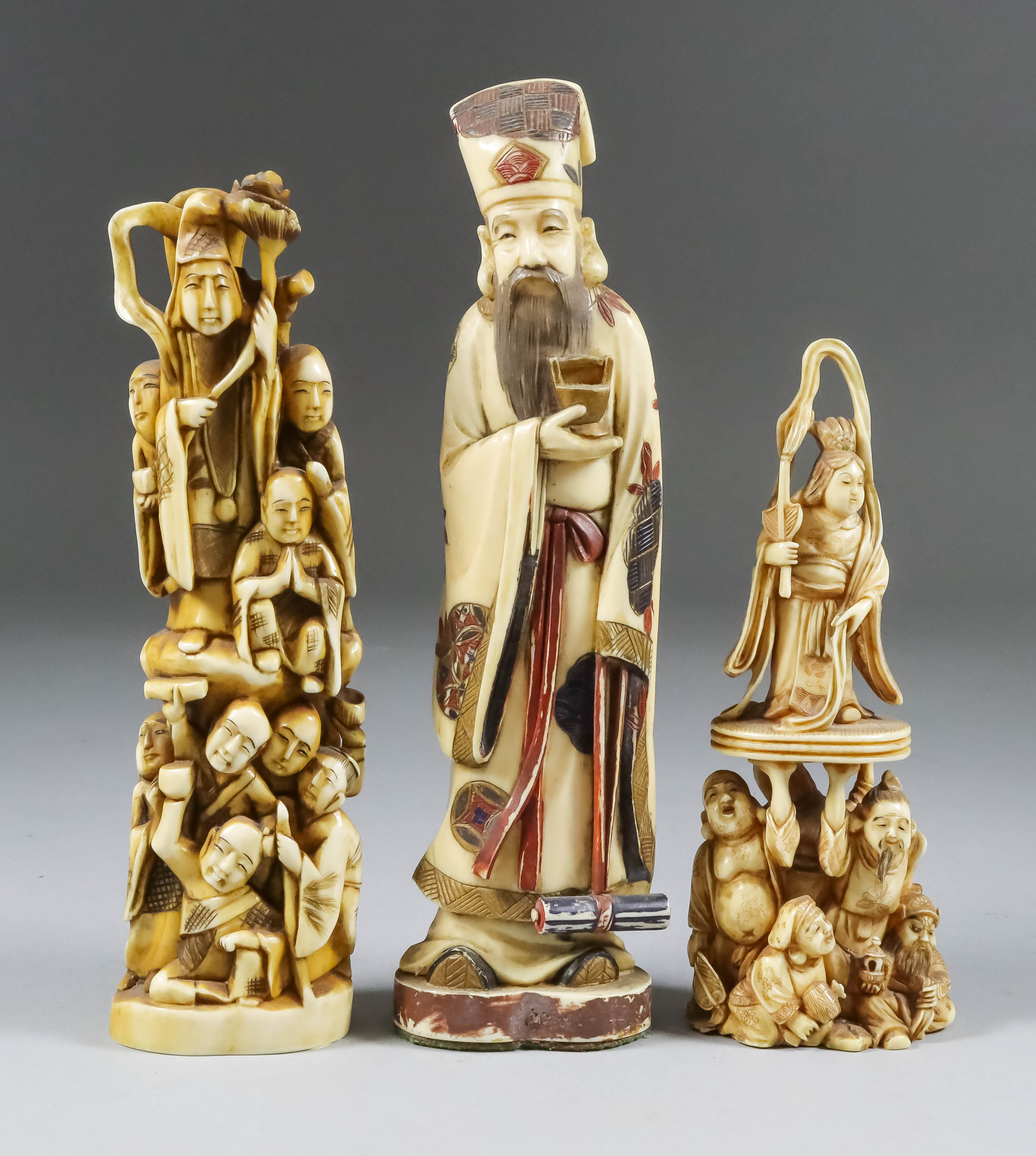 A Japanese Carved Ivory Okimono, Meiji Period, of a standing figure with nine attendants, 6.75ins (