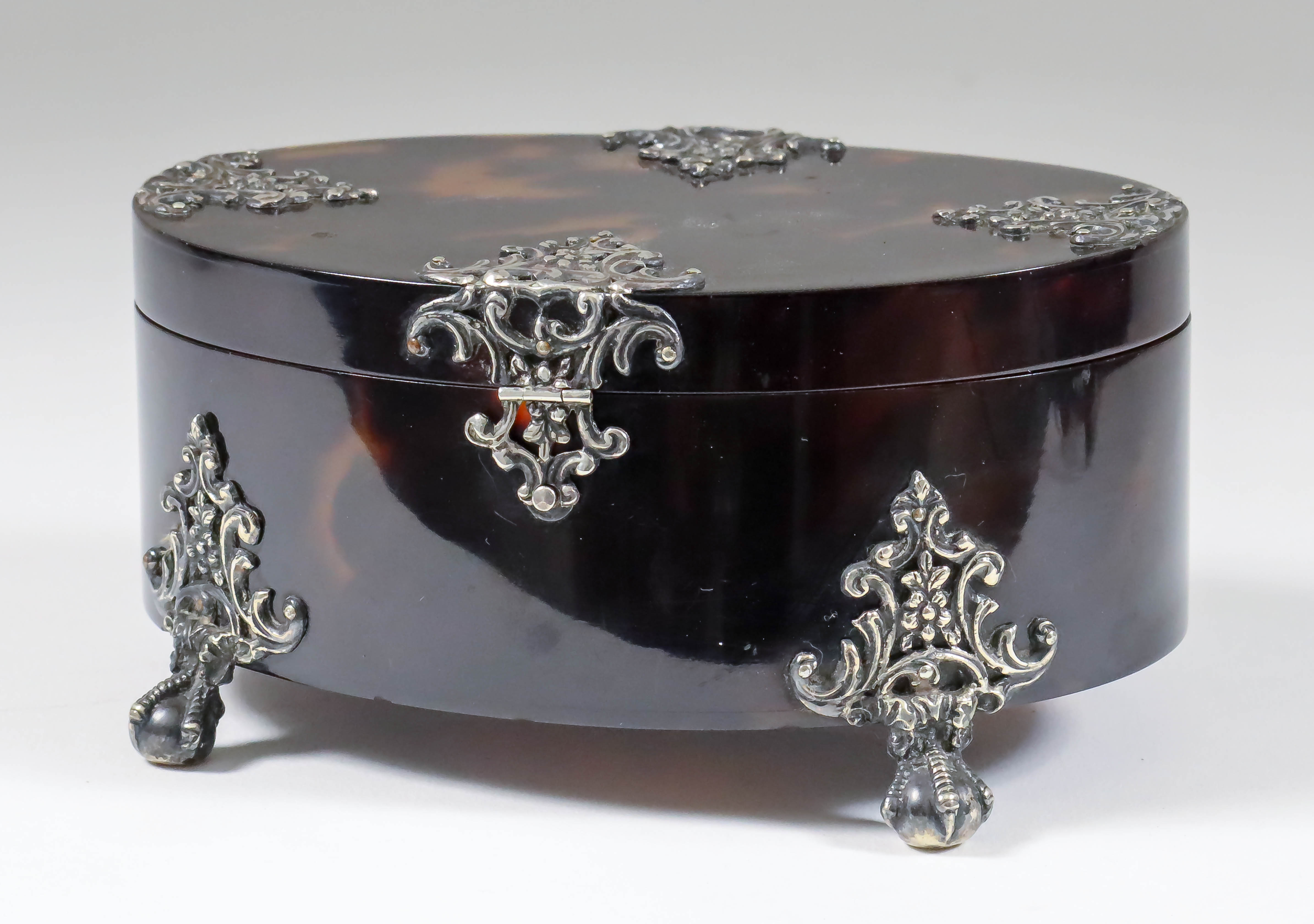 A Tortoiseshell and Silvery Metal Mounted Oval Box, the mounts pierced and cast with scroll