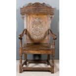 A 17th Century Panelled Oak "Wainscot" Armchair, the high back with shaped cresting carved with leaf