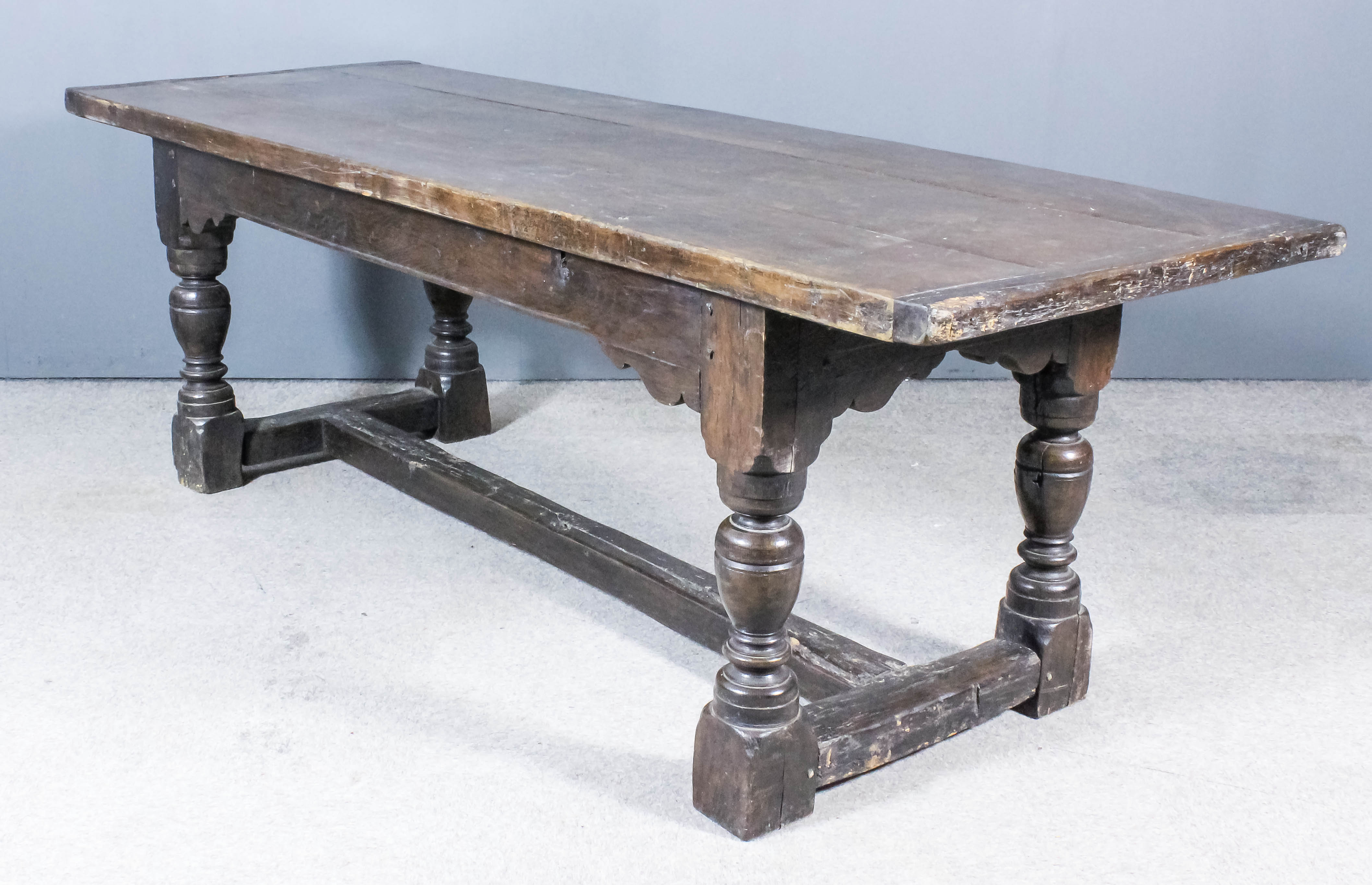 An Old Oak Refectory Table of 17th Century Design, with three-plank cleated top on heavy turned