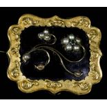 A Mourning Brooch, Victorian, in rectangular gold coloured metal mount of shaped outline cast with