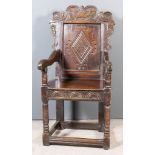 An Old Panelled Oak Wainscot Armchair of "17th Century" design, the shaped crest rail carved with