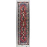 A Beluch Runner woven in colours with seven stylised star motifs on a wine ground within shaped