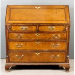 A George III Oak and Mahogany Banded Bureau, the slope enclosing central cupboard, pigeon holes