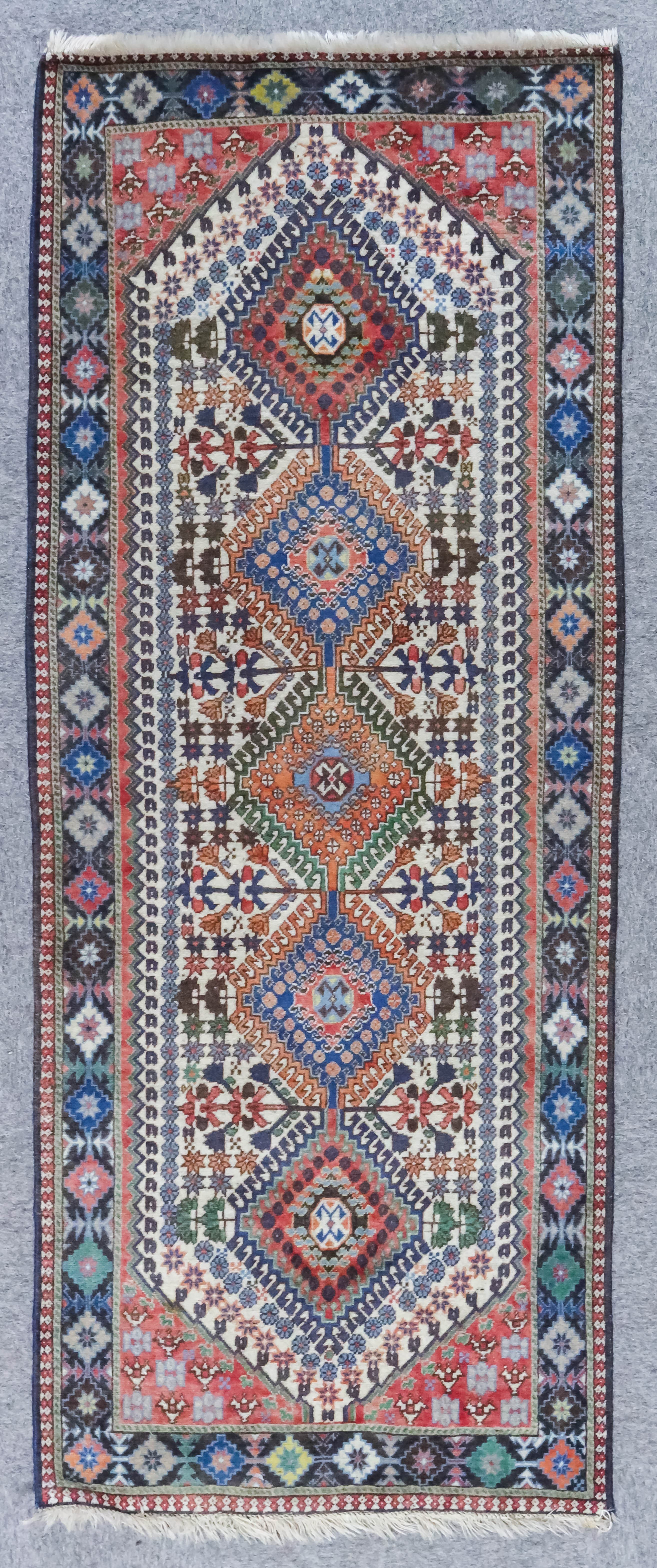 A Turkish Long Rug of Kazak Design, woven in colours with a pole medallion with five hooked lozenges