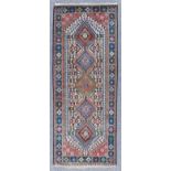 A Turkish Long Rug of Kazak Design, woven in colours with a pole medallion with five hooked lozenges
