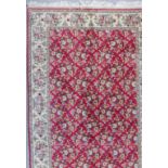 A Kirman Carpet, woven in colours with bold floral motifs in a trellis design, on a red ground,