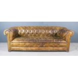 A 20th Century Chesterfield Settee, upholstered in brown hide and deep buttoned, on turned feet,
