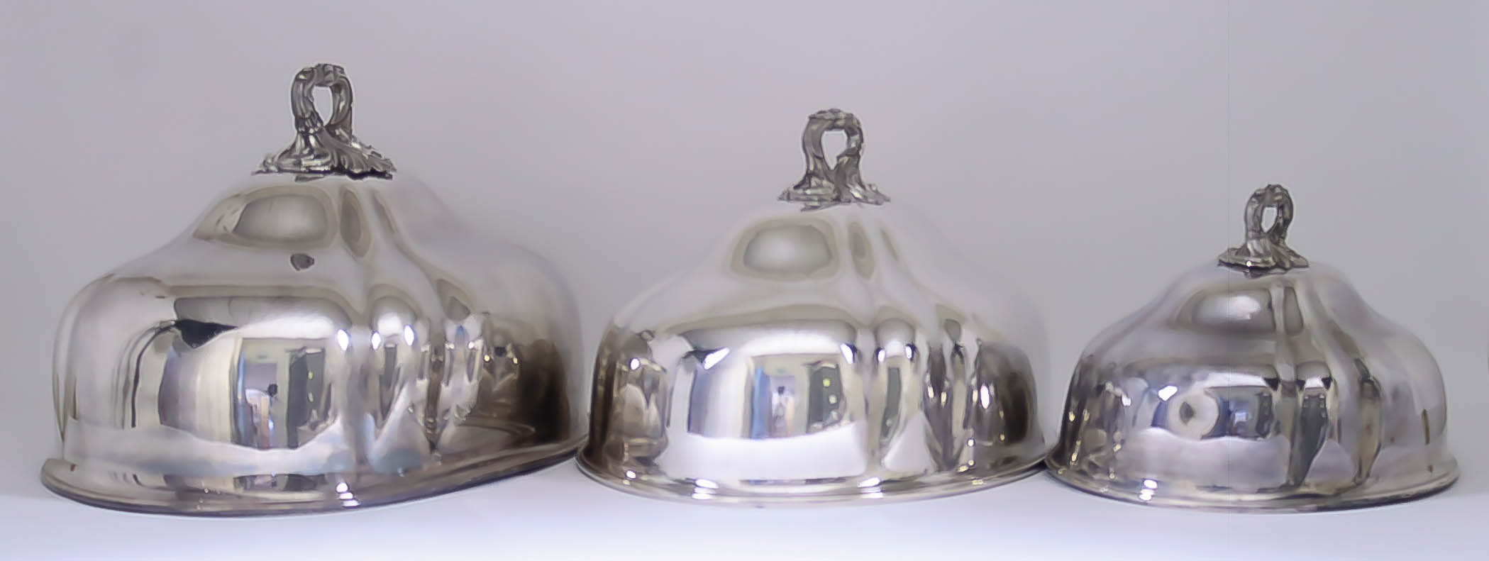 A Set of Three Victorian Plated Graduated Oval Meat Dish Covers, of slightly lobed form, the handles