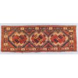A Turkmen Ersary Torba woven in colours with three bold angled and hooked motifs on a dark wine