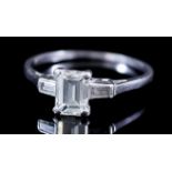 A Three Stone Diamond Ring, Modern, in platinum mount, the centre set with an emerald cut diamond,