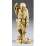 A Japanese Carved Ivory Okimono of a Standing Fisherman, Meiji, in the act of landing a carp, seal