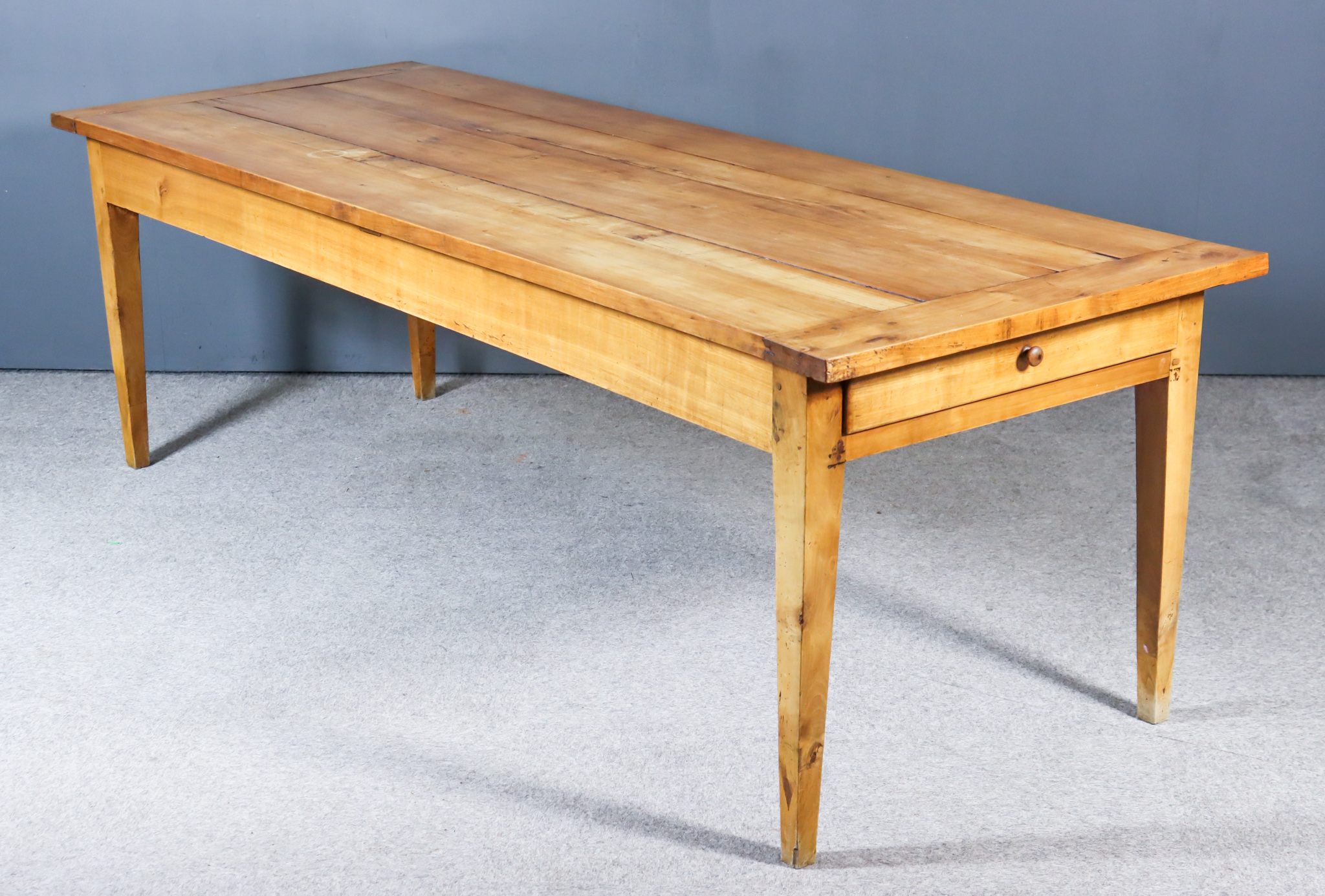 A 19th Century French Fruitwood Kitchen Table, with cleated plank top, fitted one drawer to one end,