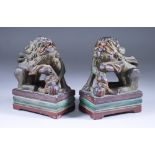 A Pair of Chinese Stoneware Fu Lions, each modelled with a ball, the surface picked out in cold