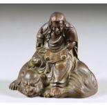 A Japanese Bronzed Metal Figural Group, of a scholar reading from a scroll, sitting on the back of a