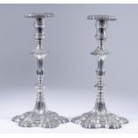 A Pair of Silvery Metal Pillar Candlesticks of "18th Century" Design, with shaped drip pans, urn